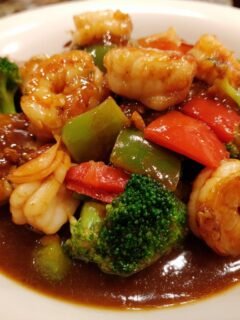 Close-up of the Aute Shrimp And Fish Recipe featuring plump shrimp, broccoli florets, and bell peppers coated in a rich brown sauce.