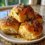 A stack of fluffy, golden Best Garlic Bread Rolls drenched in glistening garlic butter and topped with fresh parsley.