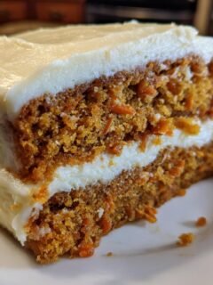 Close-up of a moist slice of Carrot Cake With Maple Cream Cheese Frosting showing two layers of cake and frosting.
