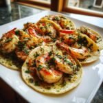 A plate featuring several delicious Cilantro Lime Shrimp Tacos topped with juicy shrimp and fresh herbs.