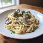 A serving of Creamy Garlic Parmesan Steak Pasta featuring fettuccine coated in a rich white sauce, topped with steak chunks and parsley.