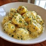 Close-up of fluffy gnocchi coated in a rich, creamy lemon herb butter sauce and sprinkled with fresh parsley.