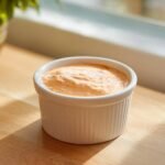 Close-up of creamy, orange-tinted Dairy Free In N Out Sauce served in a small white fluted ramekin.