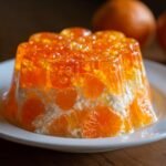 A molded, layered Easy Mandarin Orange Jello Salad featuring bright orange gelatin and mandarin segments suspended in a creamy white layer.