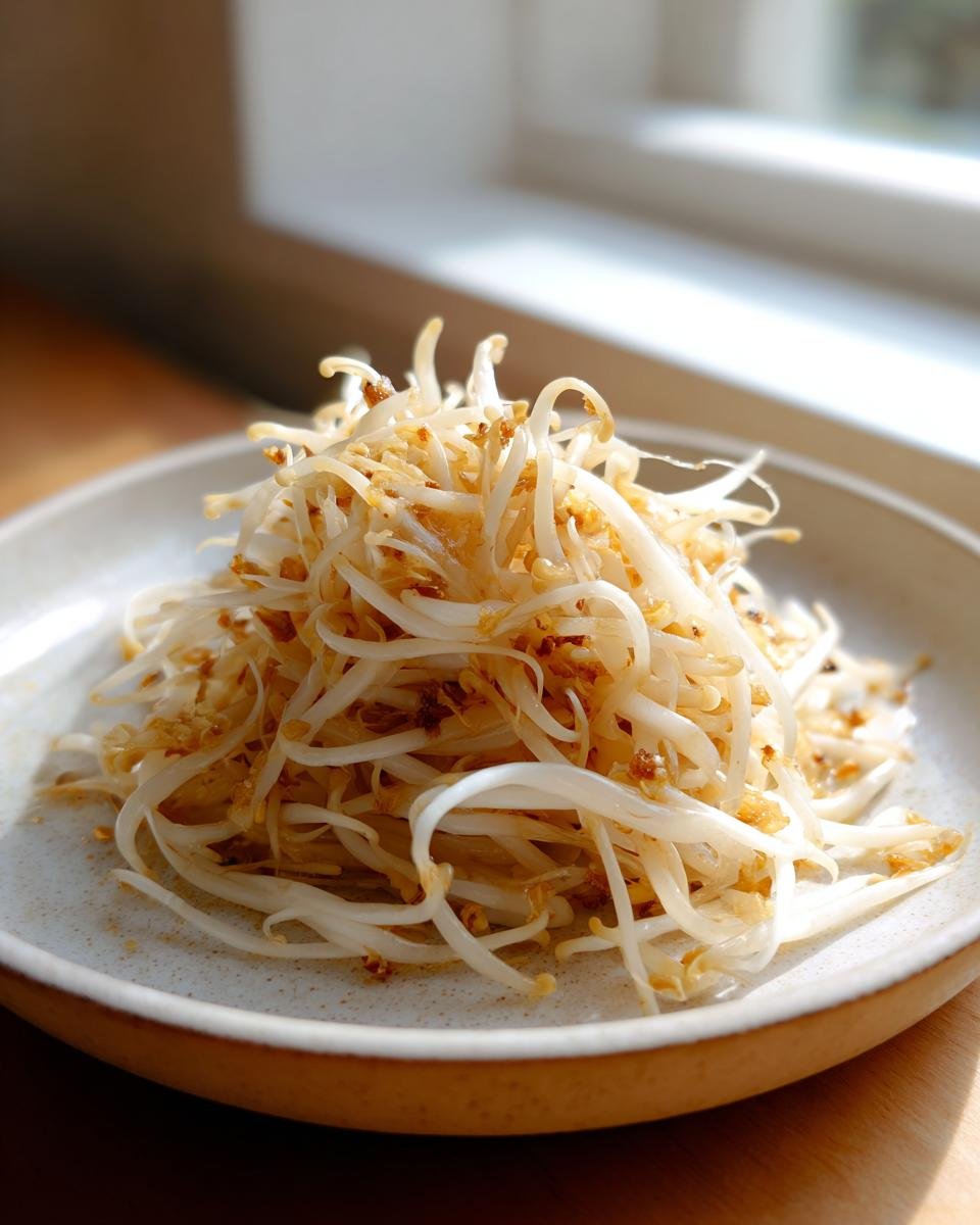 Close-up of a simple side dish made of saut&eacute;ed bean sprouts with crispy garlic, unrelated to Enoki Mushrooms Benefits.