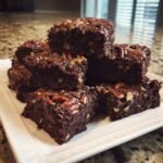 A stack of rich, fudgy squares from the Georgia Pecan Brownie Recipe, topped with glazed pecans.