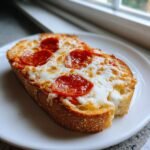 A close-up of a single slice of Kams Spooky French Bread Pepperoni Pizza with melted cheese.