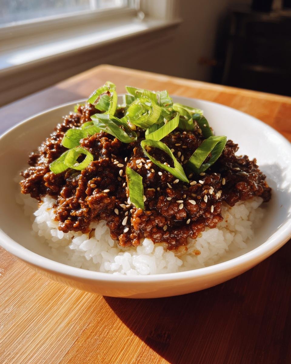 A close-up of a Korean Ground Beef Bowl featuring savory ground beef over white rice, topped with sliced green onions and sesame seeds.