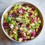 Overhead view of a large bowl filled with La Scala Chopped Salad, featuring mixed greens, radicchio, croutons, and grated cheese.