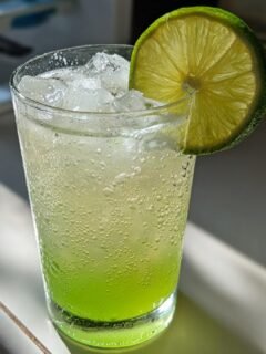 Close-up of a fizzy, bright green Lime Rickey Mocktail served over ice and garnished with a fresh lime wheel.