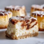 A cross-section view of one of the Mini Cinnamon Roll Cheesecakes showing the creamy texture and cinnamon swirl.