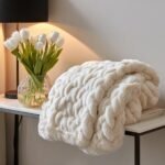 A plush, cream-colored, braided faux fur throw blanket adding texture and comfort for livable luxury in a small space.