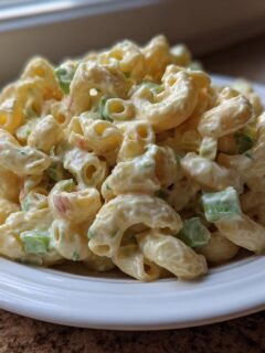 A close-up of creamy Small Batch Macaroni Salad featuring elbow macaroni, celery, and a rich dressing, served on a white plate.