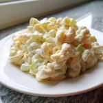 A close-up serving of creamy Small Batch Macaroni Salad featuring elbow macaroni and chopped celery on a white plate.