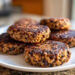 A stack of freshly seared, sturdy veggie burger patties made with rice and beans, ready to serve.