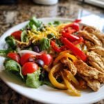A vibrant plate featuring a Tasty Chicken Fajita Salad with grilled chicken strips, saut&eacute;ed peppers, lettuce, tomatoes, and cheese.