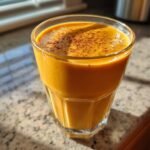 Close-up of a thick, orange-colored Best Autumn Smoothie Recipe topped with cinnamon.