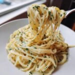 A fork lifting a generous portion of creamy 5 Ingredient Garlic Parmesan Pasta, coated in sauce and sprinkled with parsley.