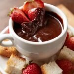 Close-up of a white mug filled with rich Chocolate Fondue Recipe, garnished with fresh strawberries.