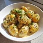 A close-up of baby potatoes smothered in a rich Creamy Garlic Sauce and topped with fresh parsley.
