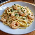 A close-up of a serving of Creamy Garlic Shrimp Pasta topped with fresh parsley and grated cheese.