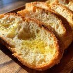 Close-up of toasted Garlic Bread With Sliced Bread, glistening with melted butter or oil and sprinkled with herbs.
