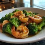 Close-up of cooked shrimp and bright green broccoli florets coated in garlic butter sauce.