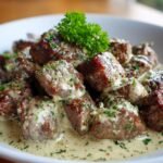 Close-up of tender Garlic Butter Steak Bites smothered in a rich Parmesan cream sauce and garnished with parsley.