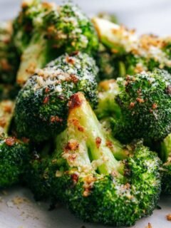 Close-up of vibrant green roasted broccoli florets topped with melted cheese and breadcrumbs for Garlic Parmesan Broccoli.