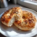 Two everything bagel halves showing the fluffy interior of the High Protein Greek Yogurt Bagels on a white plate.