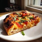 A thick, airy slice of Homemade Margherita Pizza with melted cheese, red sauce, and fresh basil.