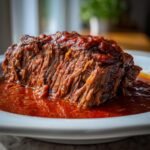 Close-up of a fork-tender piece of Italian Pot Roast Stracotto covered in a rich, deep red tomato sauce.