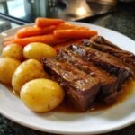 Slices of tender Korean Style Pot Roast served with small boiled potatoes and carrots on a white plate.