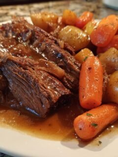 A close-up of tender Korean Style Pot Roast served with glazed carrots and potatoes in rich brown gravy.