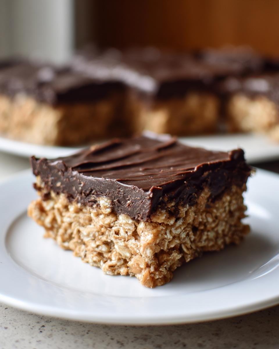 A close-up of one square of No Bake Chocolate Peanut Butter Oat Bars with a thick chocolate topping.