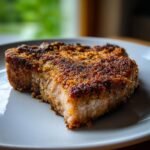 A perfectly cooked Parmesan Crusted Pork Chop with a thick, golden-brown, crispy topping on a white plate.