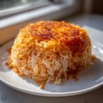 A perfectly molded mound of Persian Tomato Rice showing the crispy, golden tahdig crust on top.