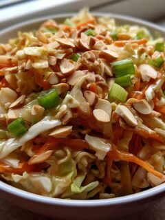 Close-up of a vibrant Ramen Noodle Salad With Cabbage, topped with sliced almonds and green onions.