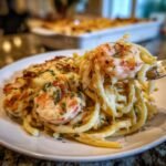 A fork lifting a bite of creamy Shrimp Scampi Pasta Bake topped with melted cheese and parsley.
