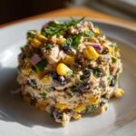 A molded serving of Southwest Chicken Salad featuring chicken, black beans, corn, and red onion, topped with cilantro.